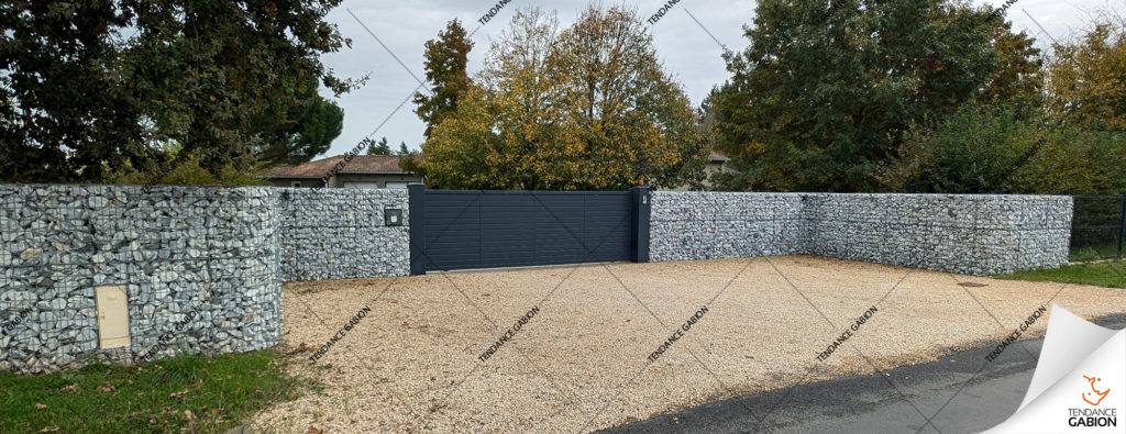 Clôture en gabion entourant un portail d'entrées d'une maison.